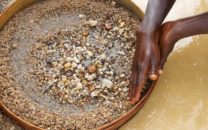 Female artisanal and small-scale miner panning for minerals.